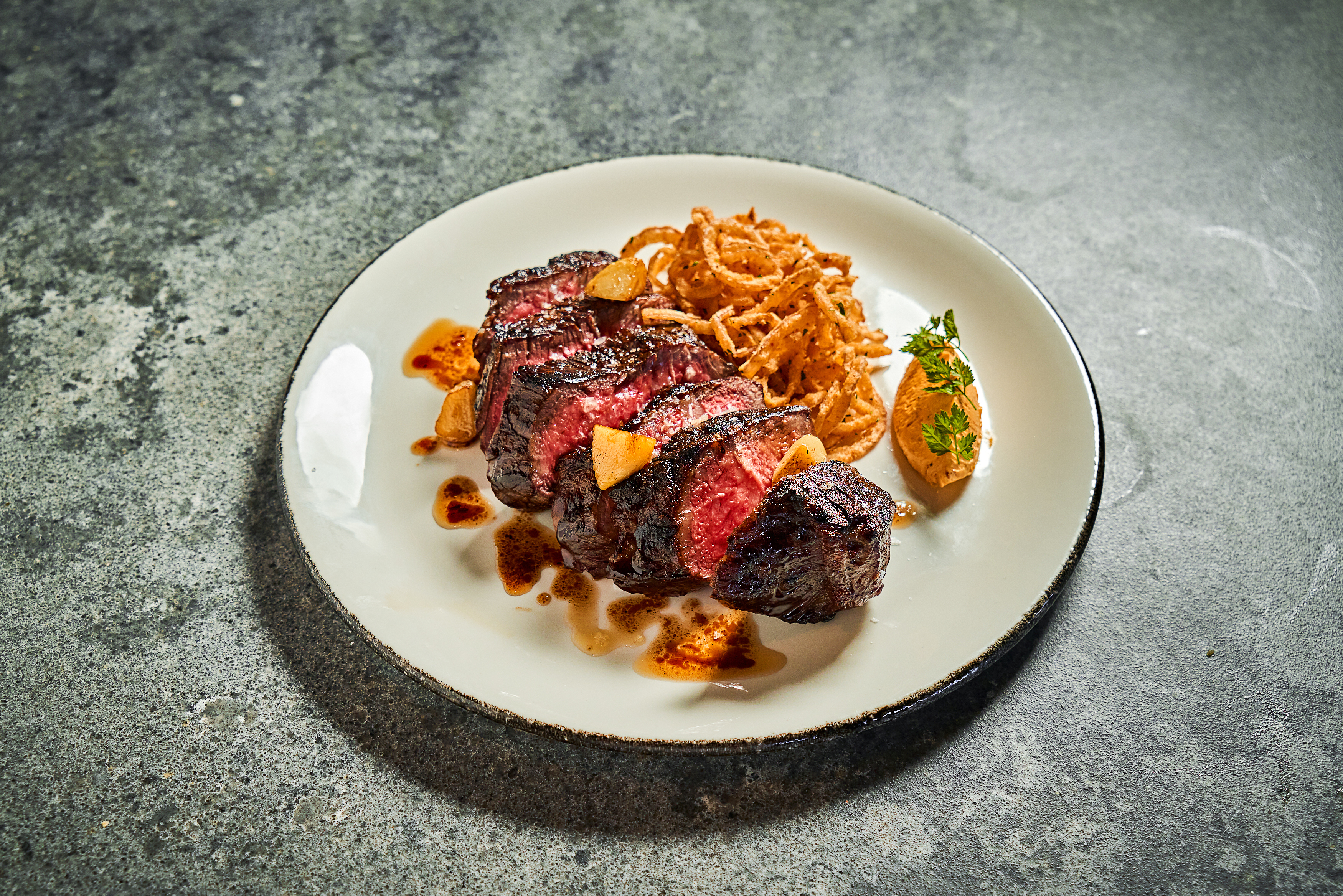 a steak on a plate with crispy onions