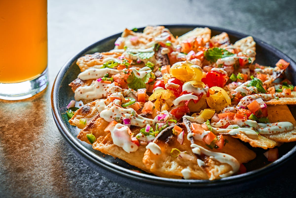 vibrant bowl of crispy corn chips with peppers, pico de gallo and crema 