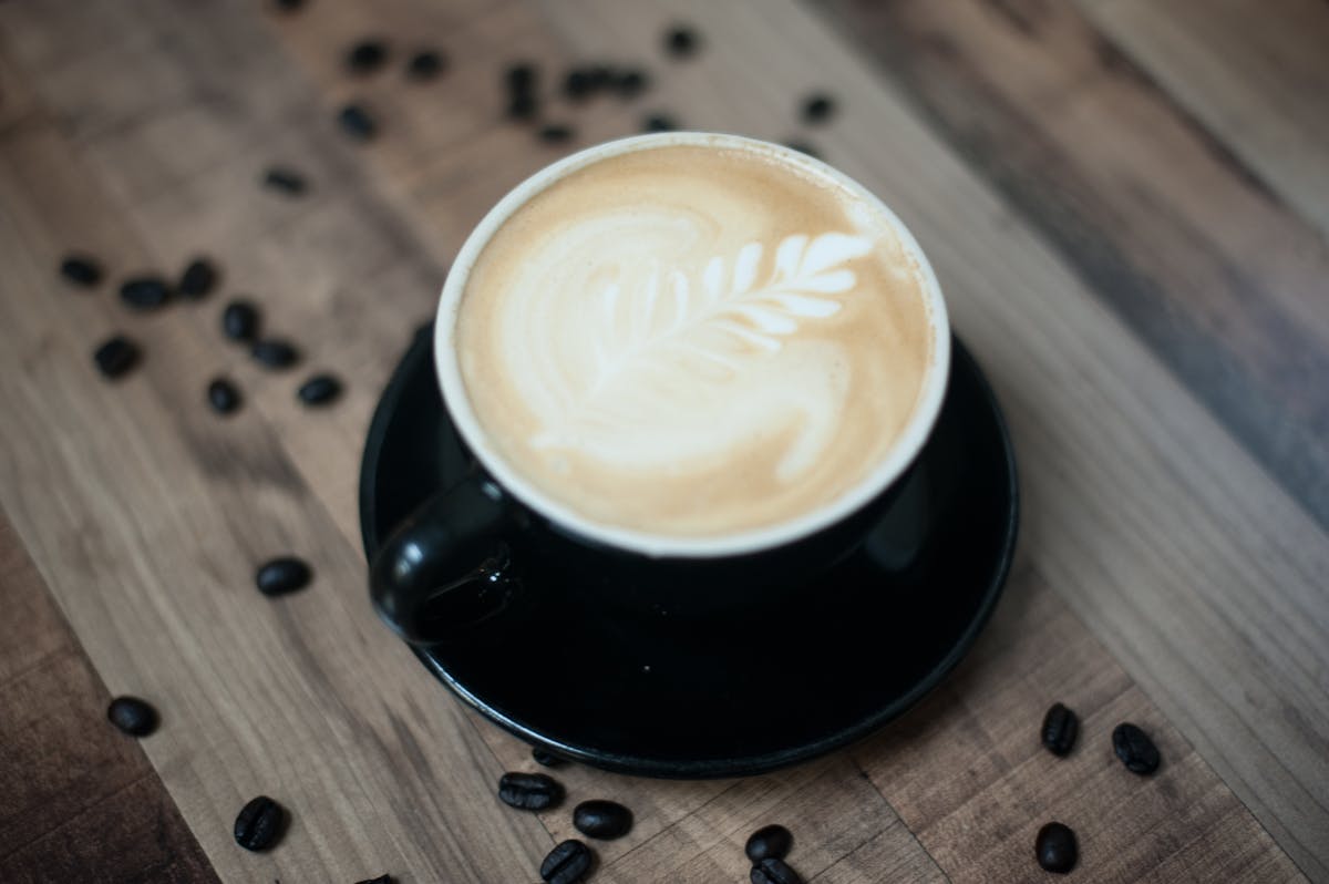 a cup of coffee sitting on top of a wooden table