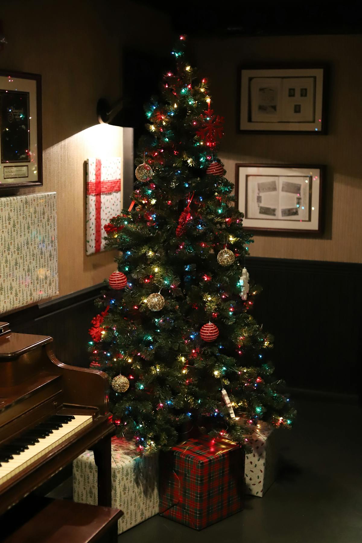 a piano in a dark room with a christmas tree