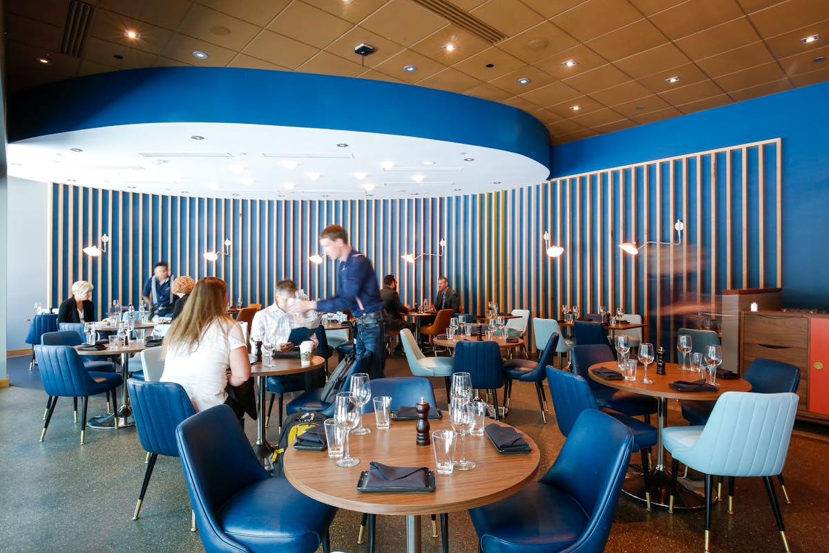a group of people sitting at a table with a blue chair
