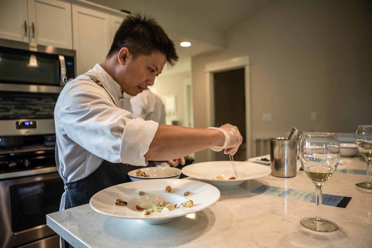 a person holding a plate of food on a table