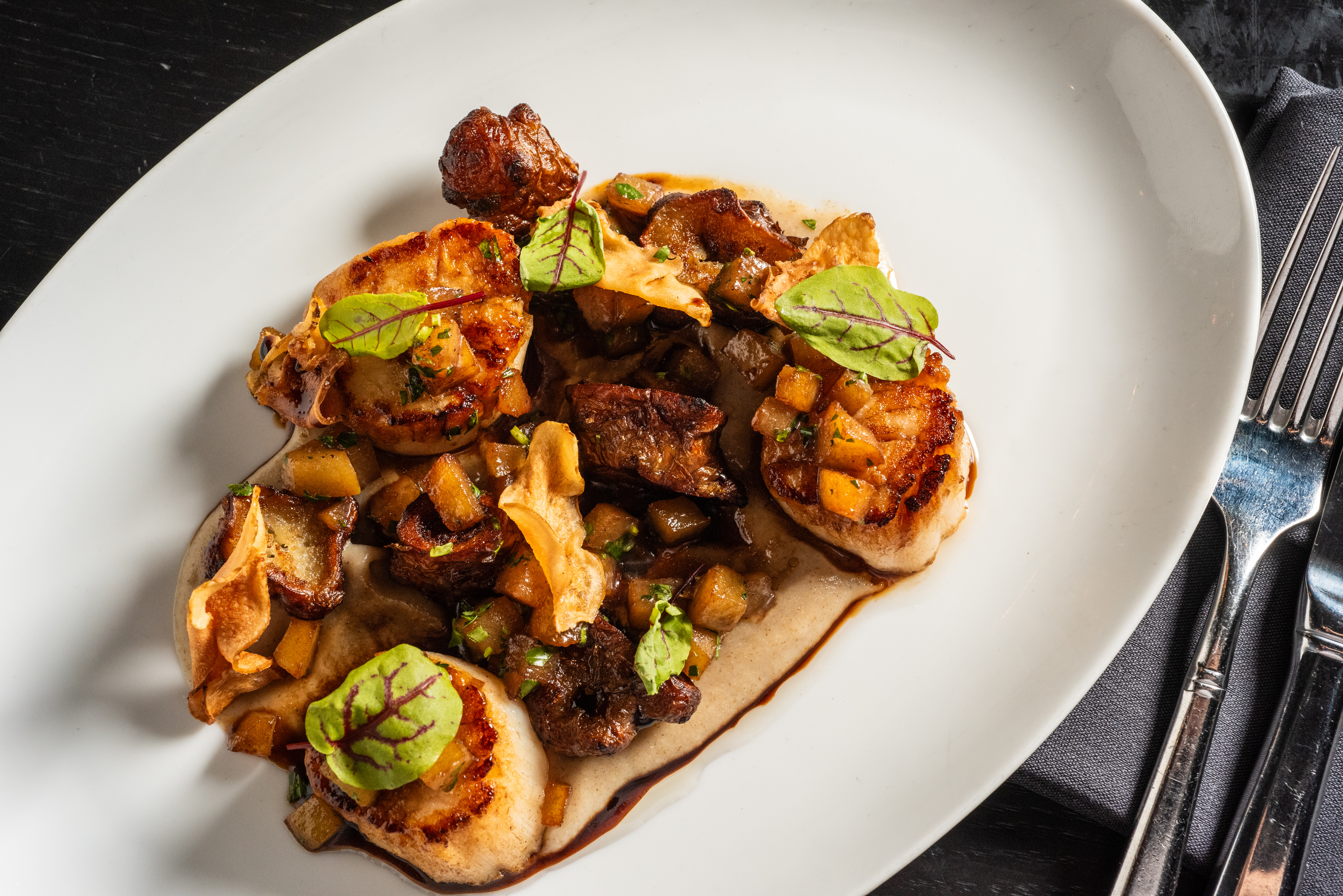 a plate of scallops with green garnish