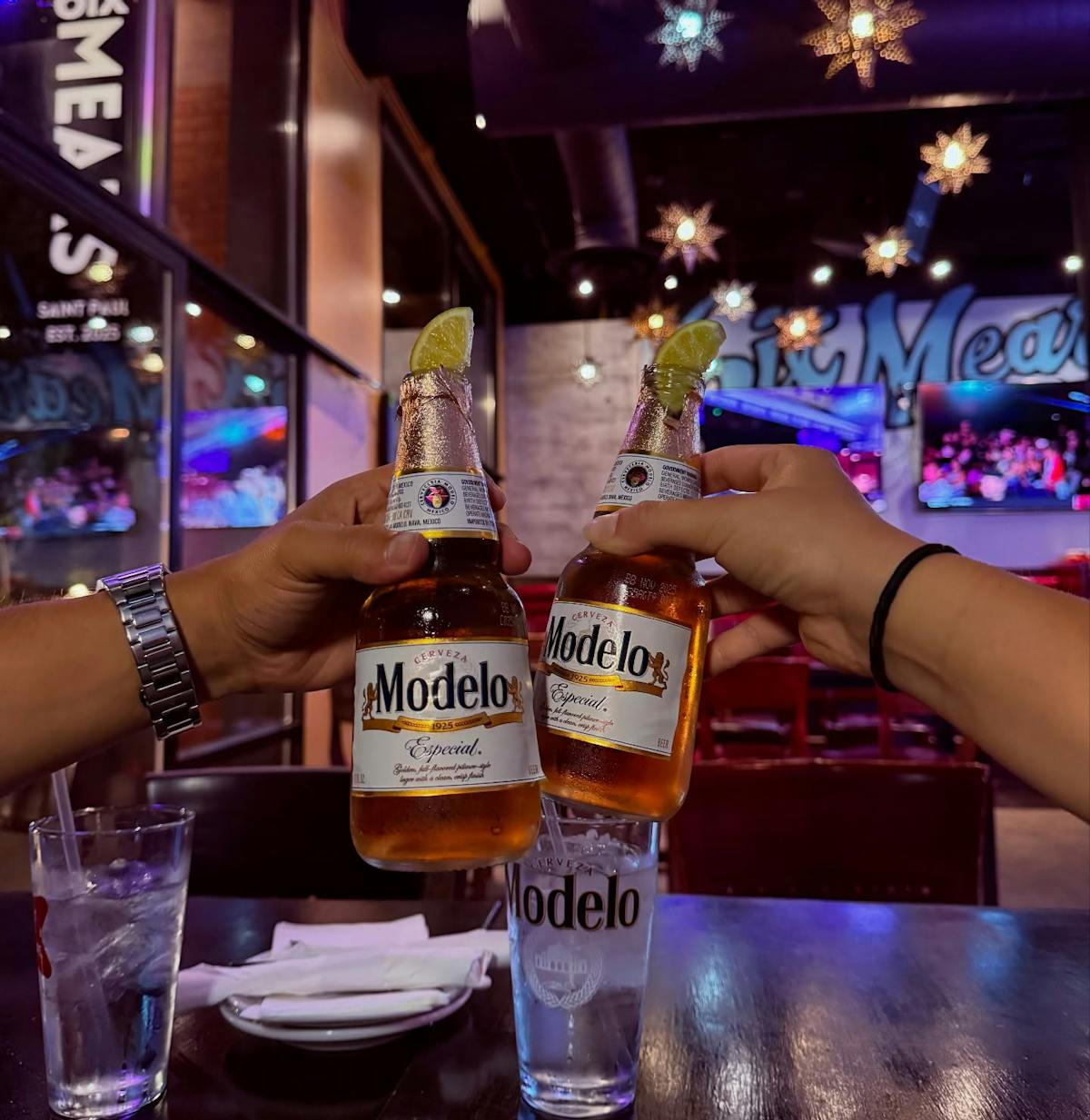 a group of hands holding bottles of beer