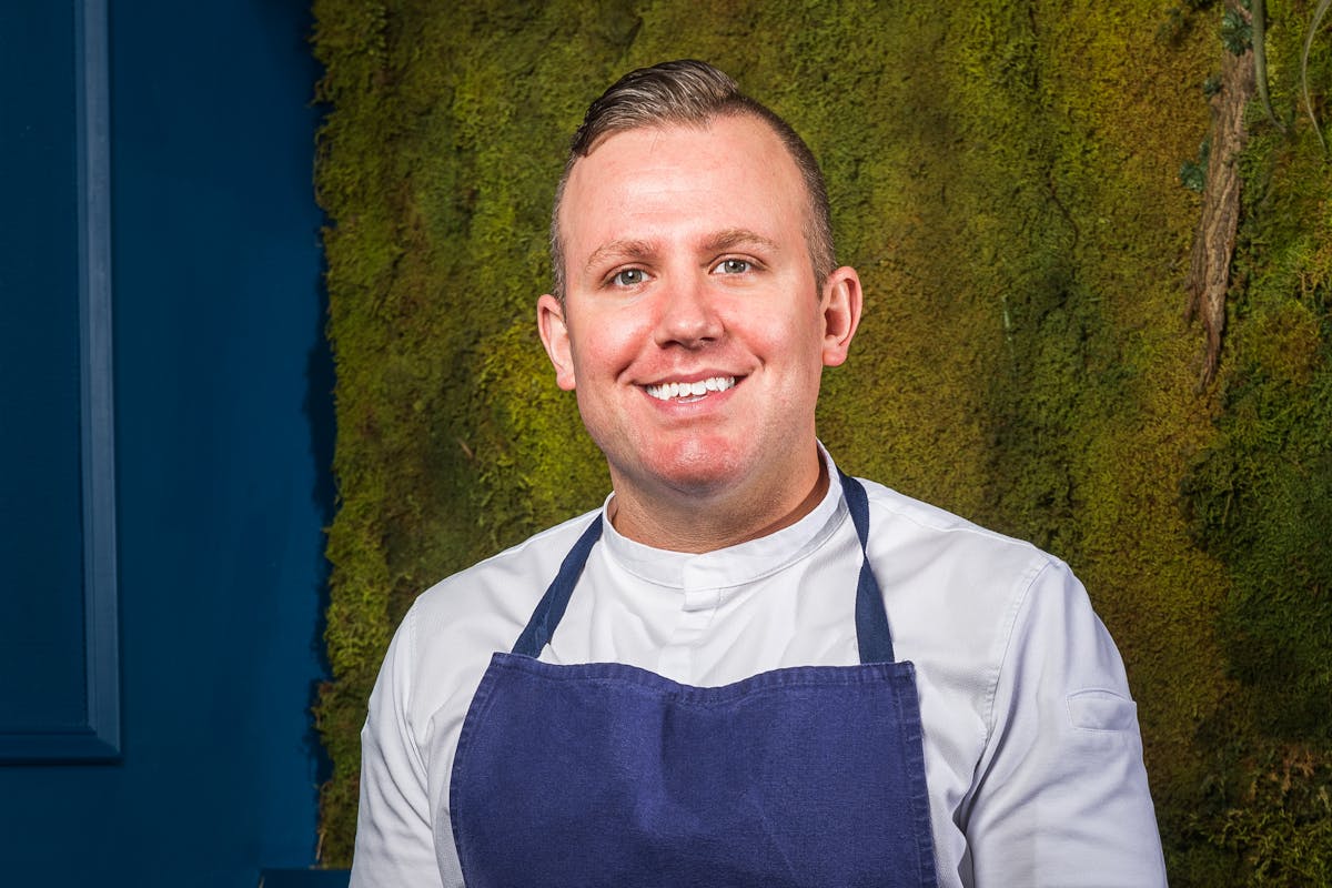 a man wearing a blue shirt and smiling at the camera