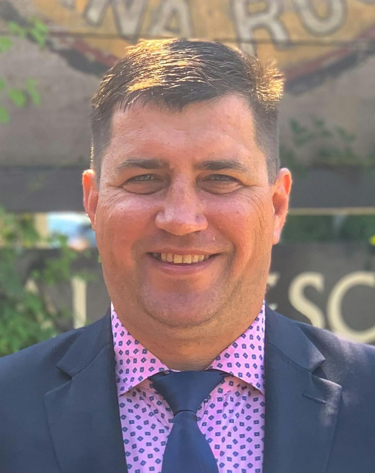 a man wearing a suit and tie smiling at the camera