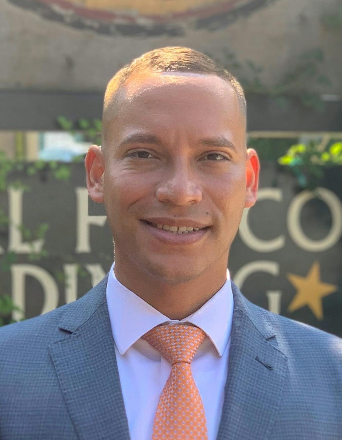 a man wearing a suit and tie smiling at the camera