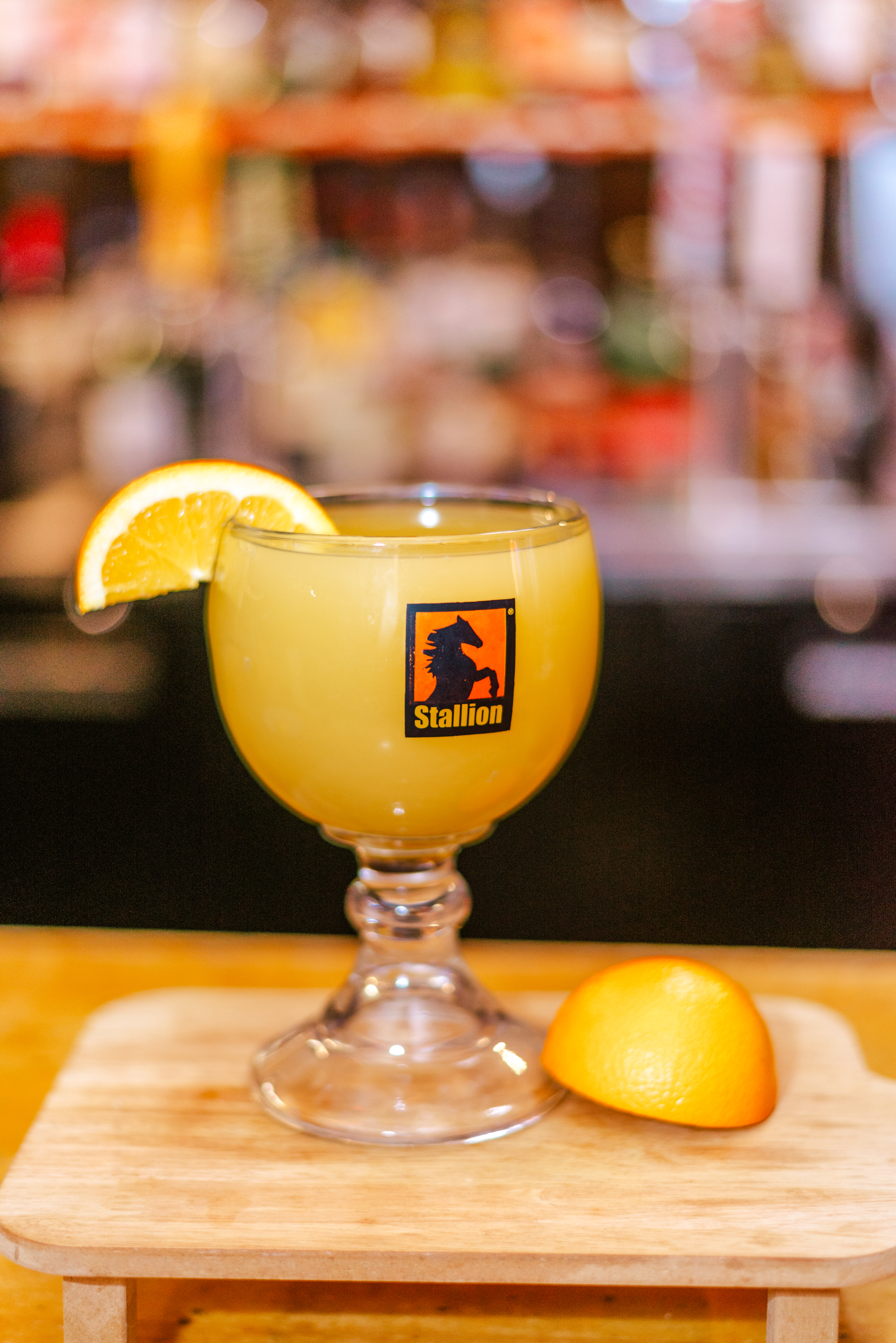 a glass of orange juice with a slice of orange on a cutting board