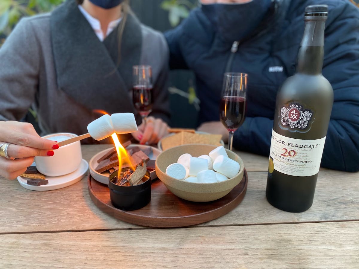 a group of people sitting at a table with a bottle of wine