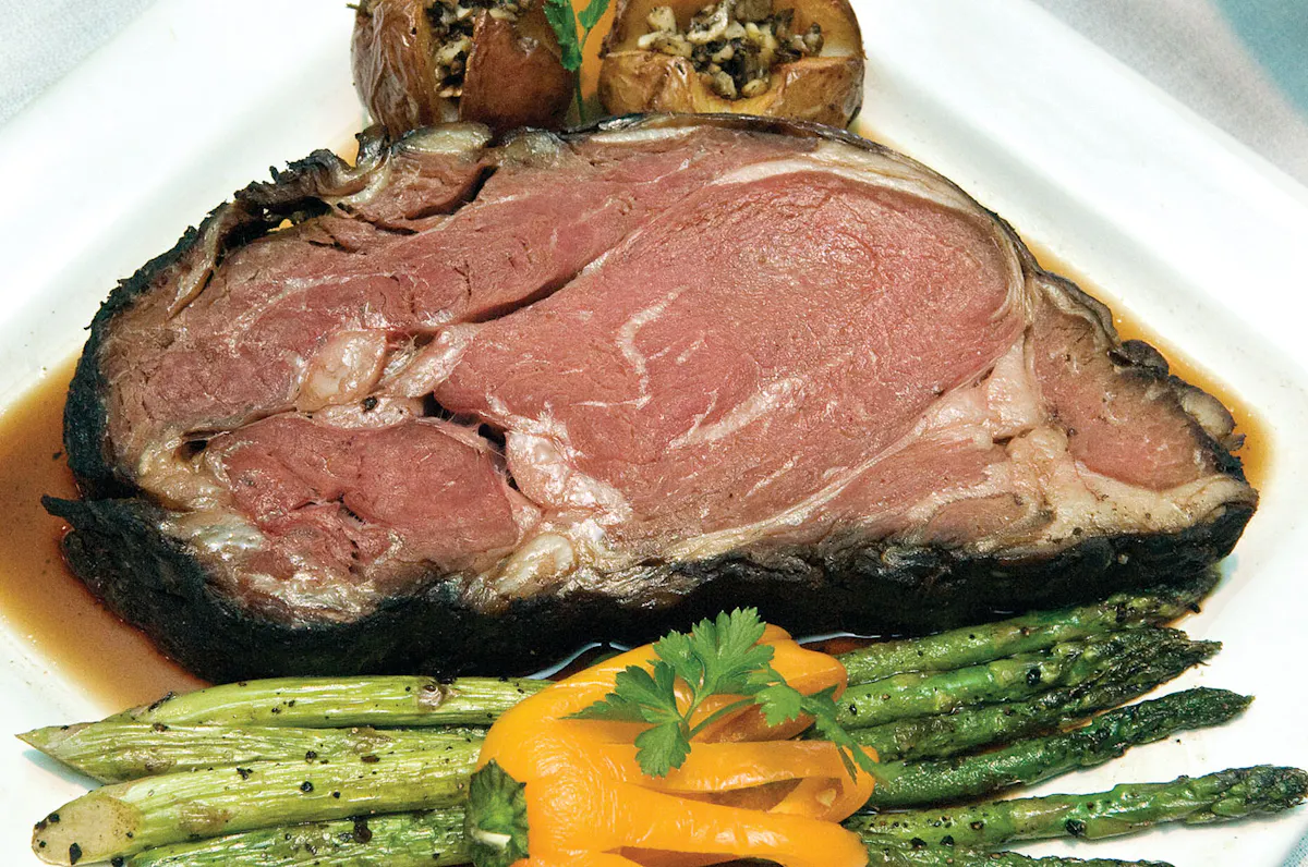 a white plate topped with a big meat steak and vegetables