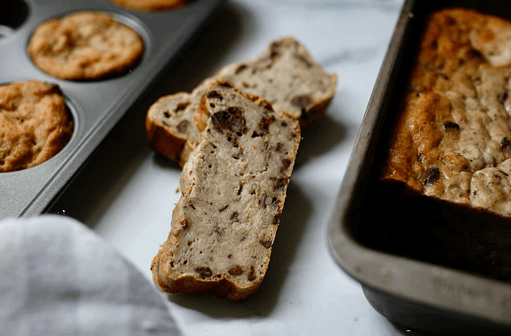 two slices of banana bread next to two baking dishes of banana bread