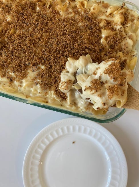 mac and cheese being scooped from a casserole dish