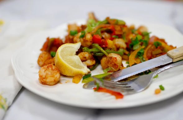 shrimp on a plate with a lemon wedge and fork and knife