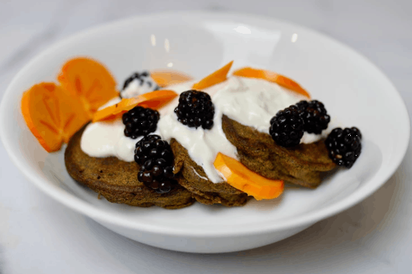 pancakes on a white plate with cream and fruit