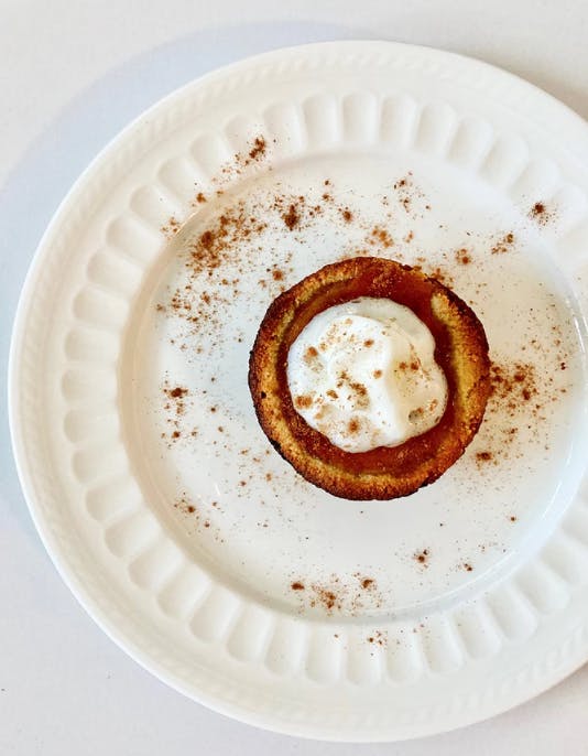 white plate with a mini pumpkin pie and whipped cream