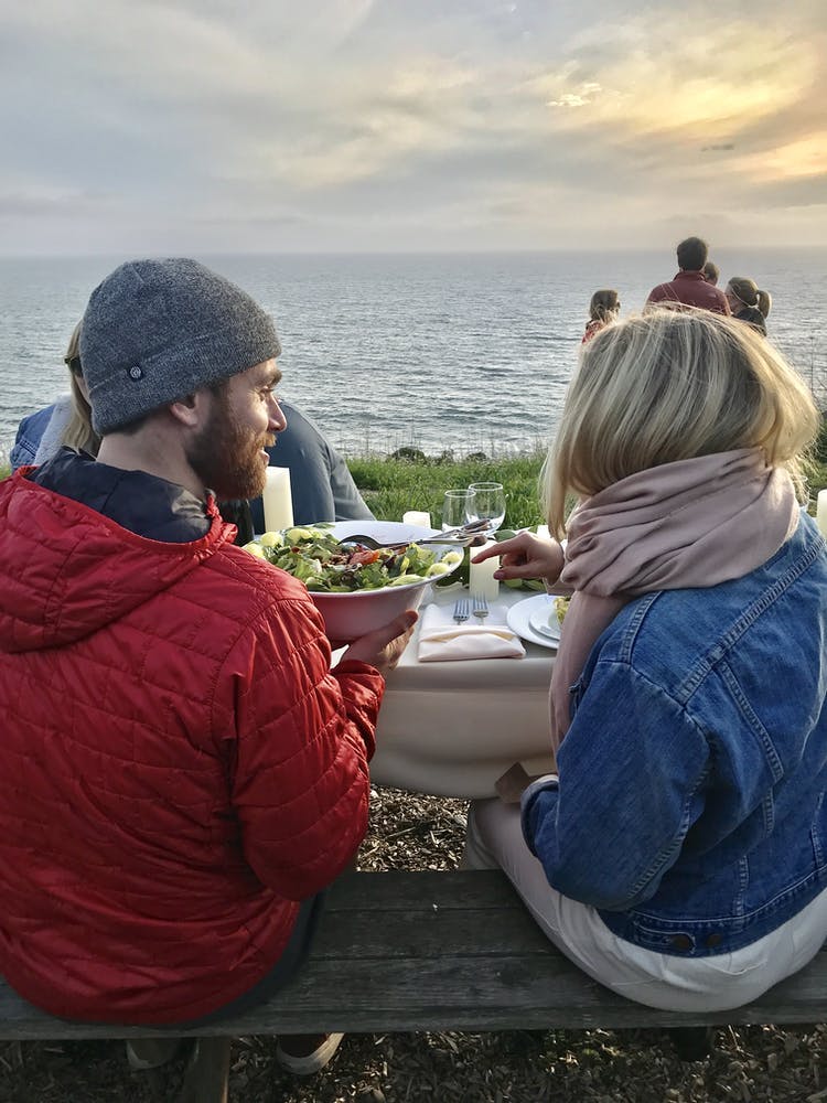 a group of people sitting on a bench near the water