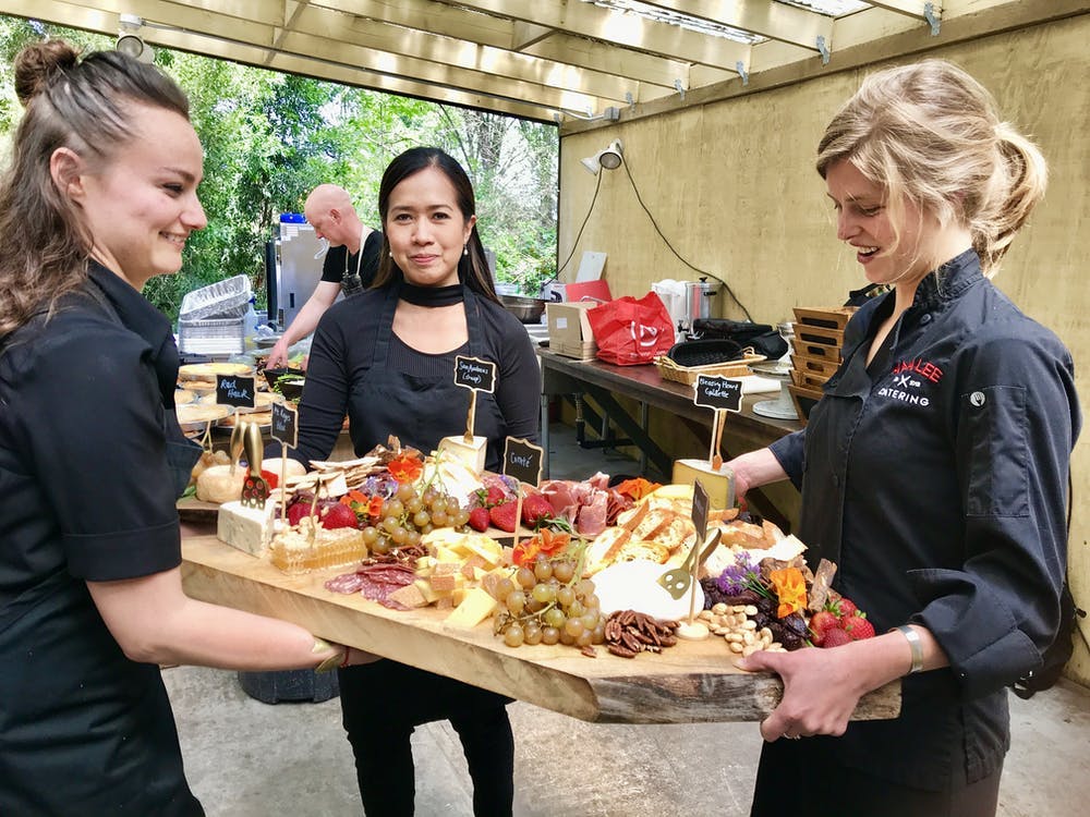 a group of people standing around a table eating food