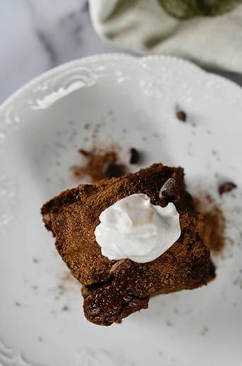 a brownie on a plate topped with whipped cream