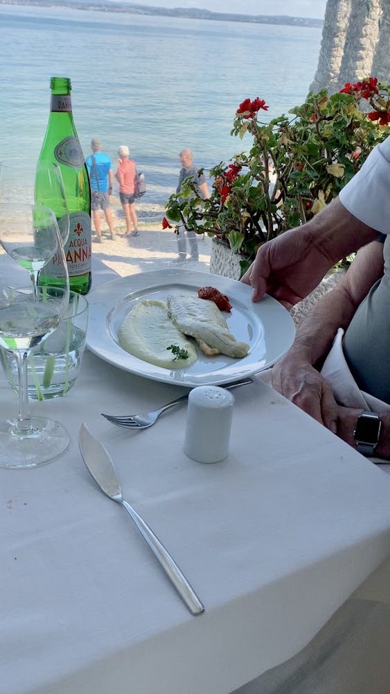 a white plate of fish being served next to a body of water