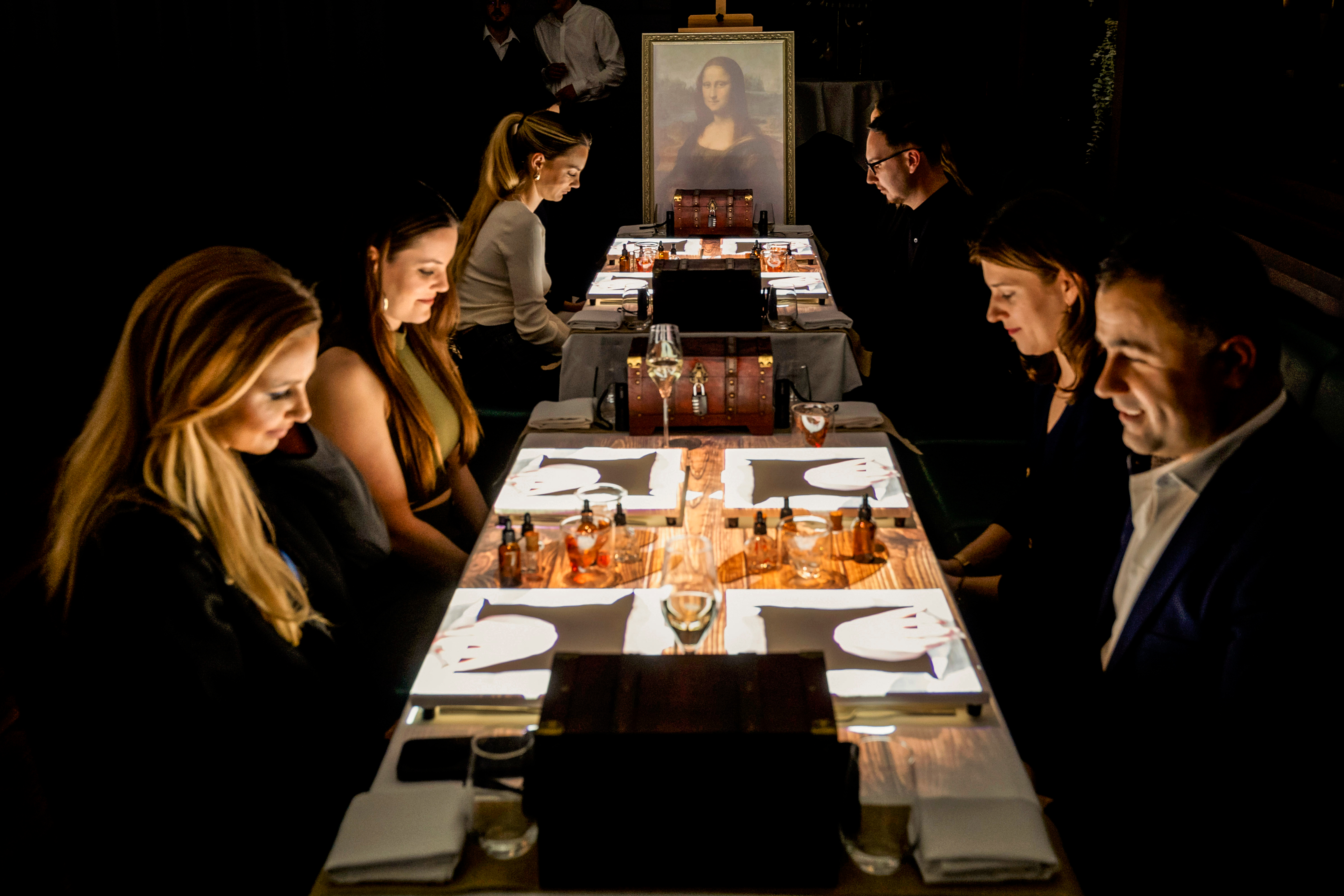 6 people enjoying the 7 paintings show dinner experience. Mona Lisa in the background.