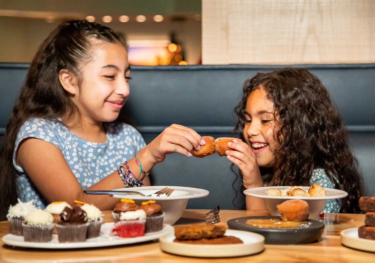 two kids eating desserts and laughing