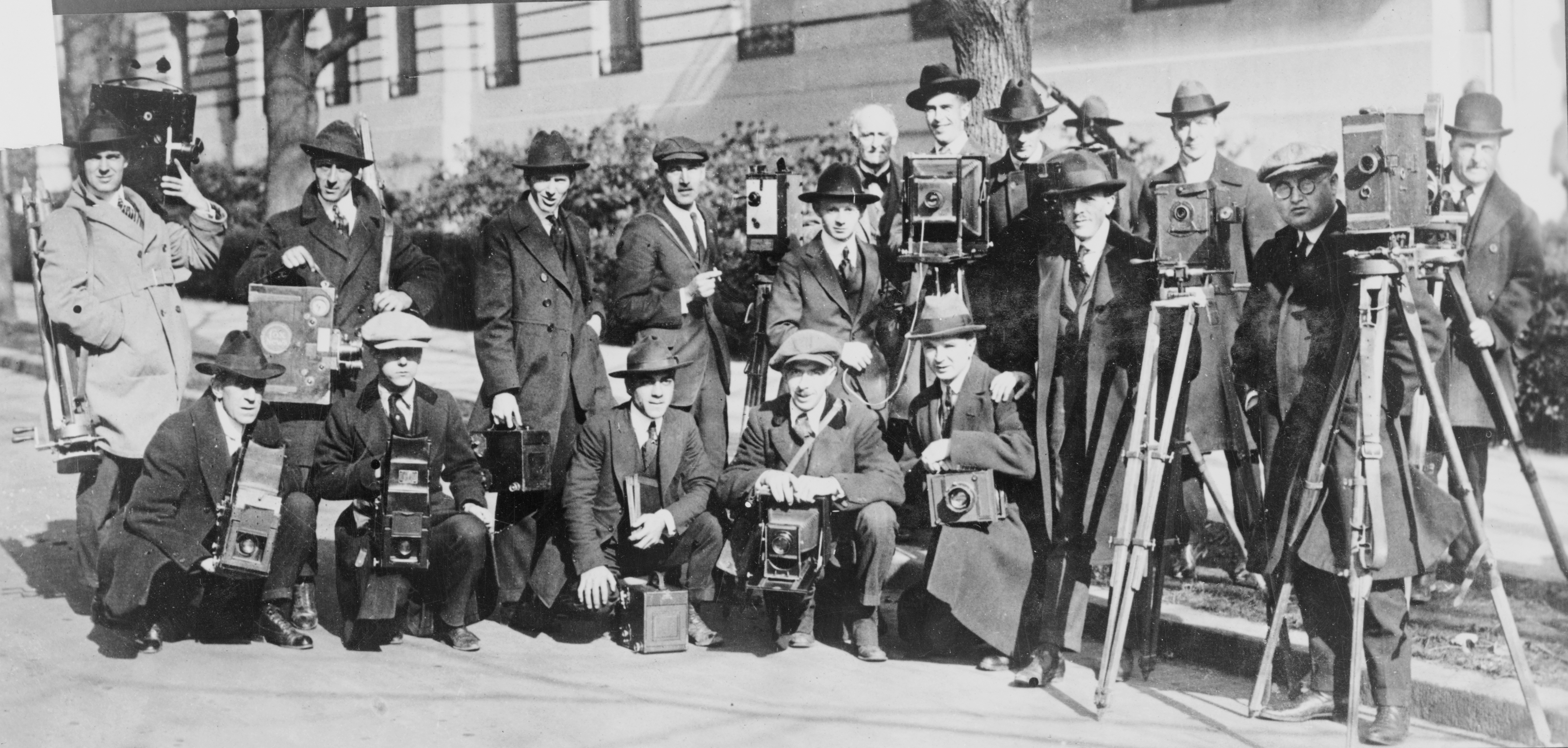 old black and white image of a group of photographers and journalists in front of the white house. Published between 1922 and 1926.