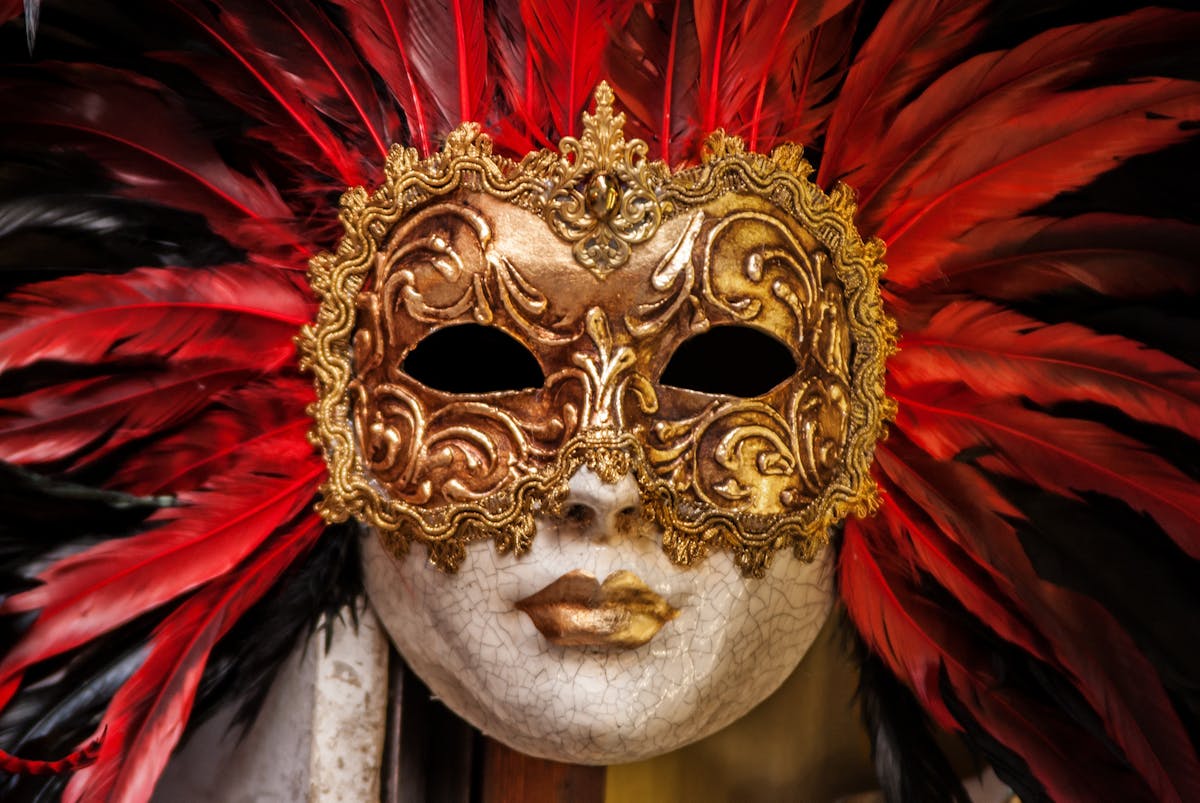 Golden Venetian mask adorned with red feathers