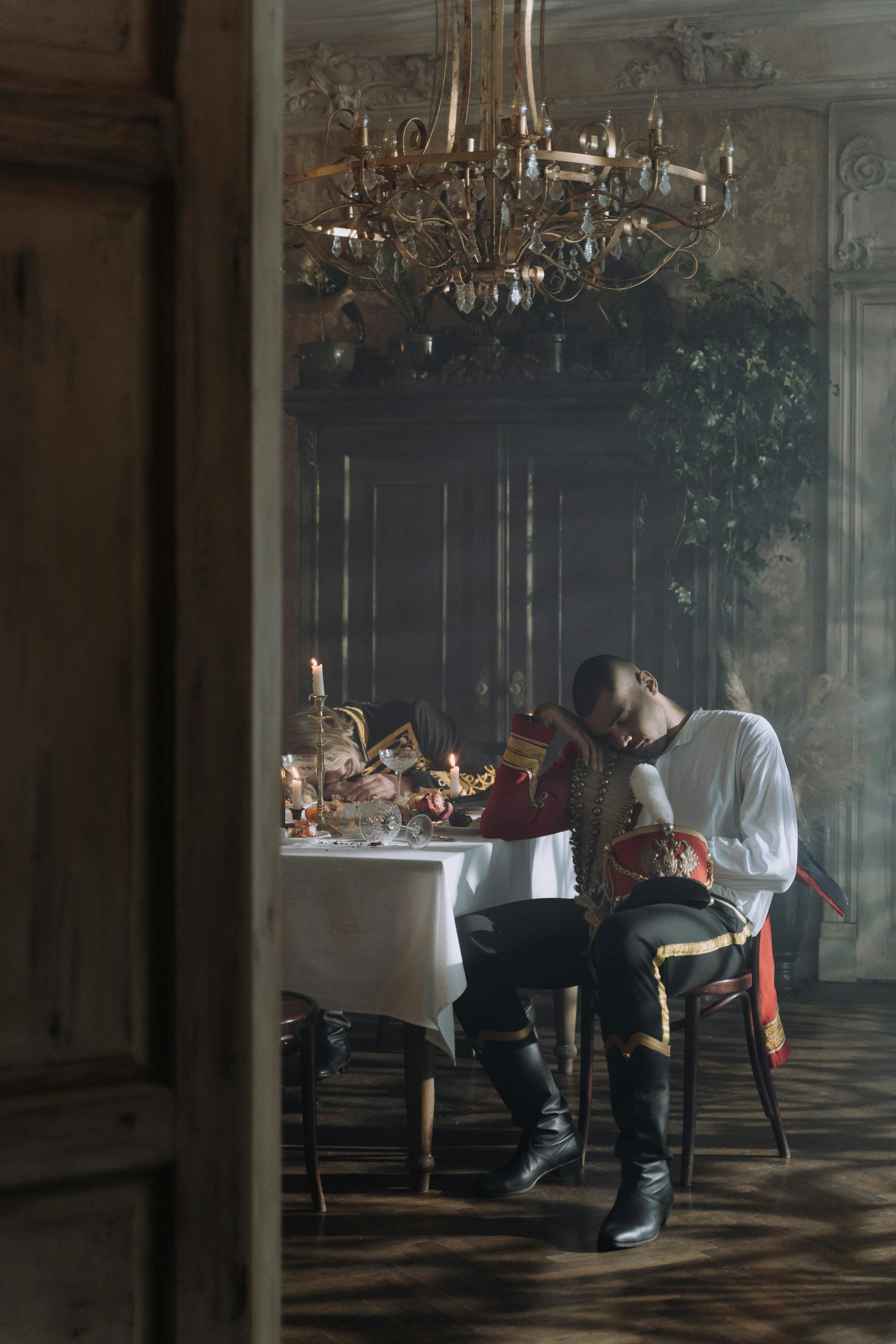 Two people hung over at a dinner table. This image is a period picture.