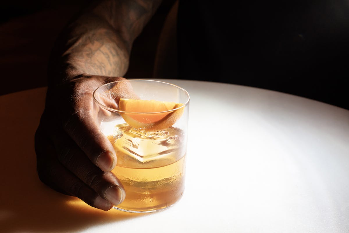 a hand holding a glass of beer on a table