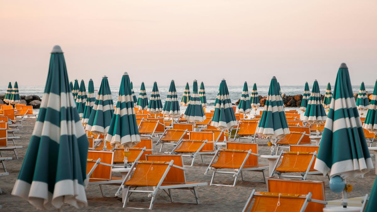 a row of beach chairs and an orange umbrella