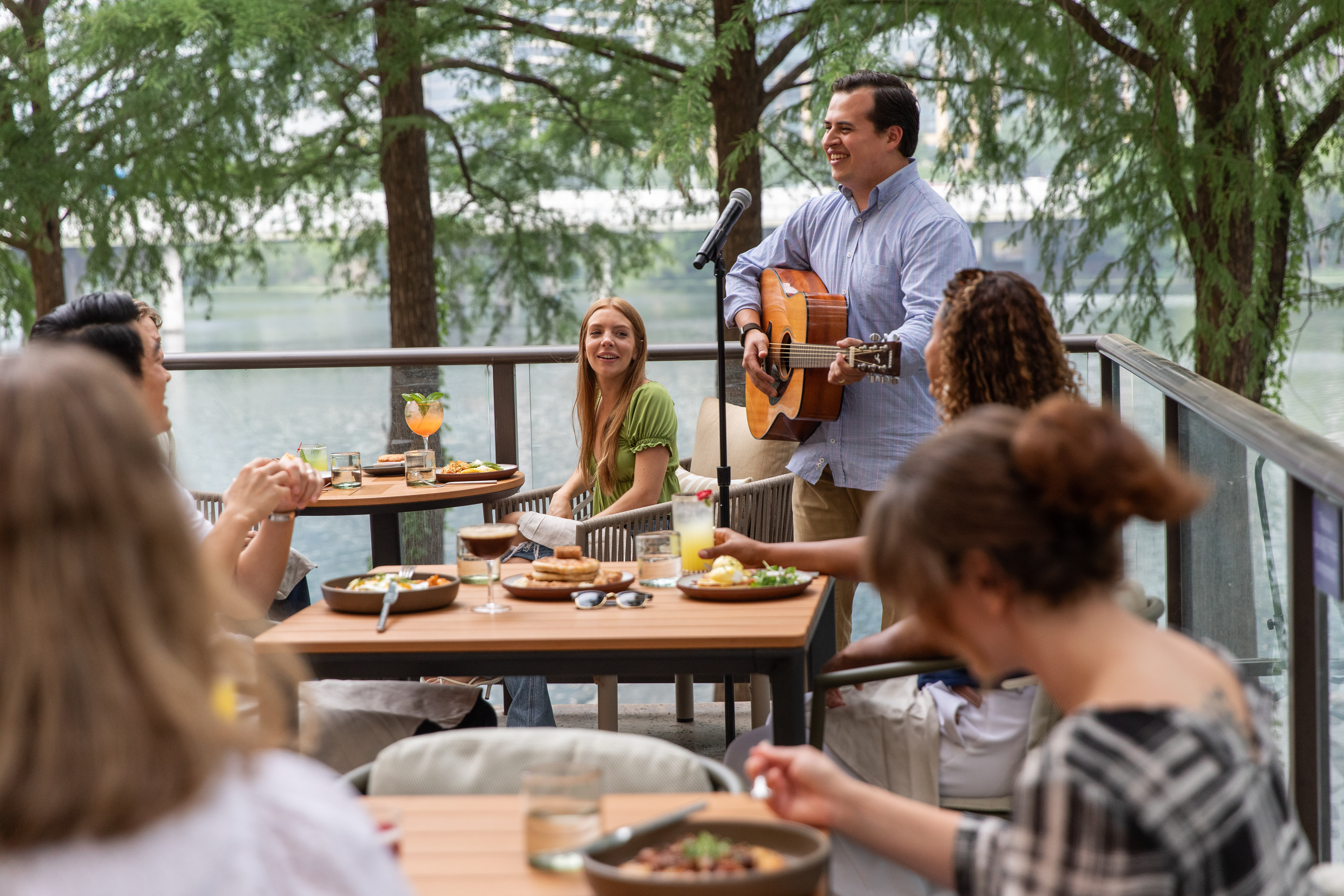 a man playing a guitar and singing to a group of people sitting at tables