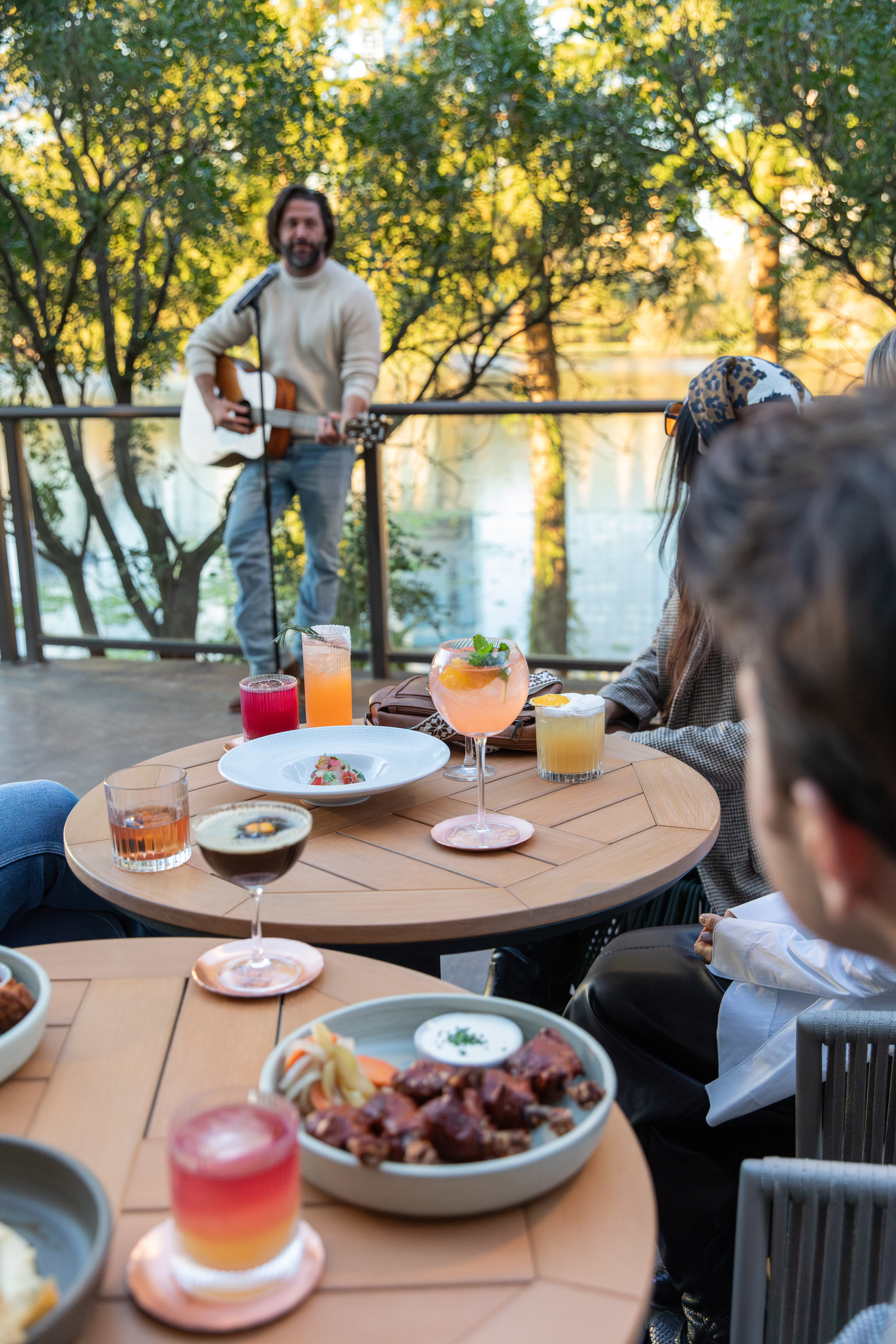 a man playing guitar on a table with food and drinks