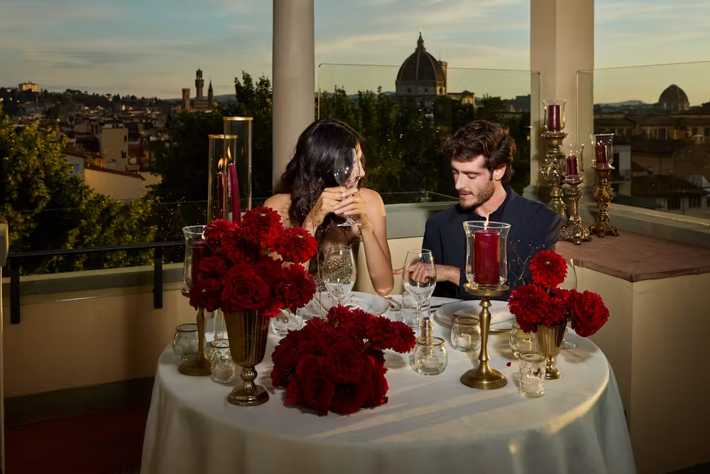 a person sitting at a table with a vase of flowers