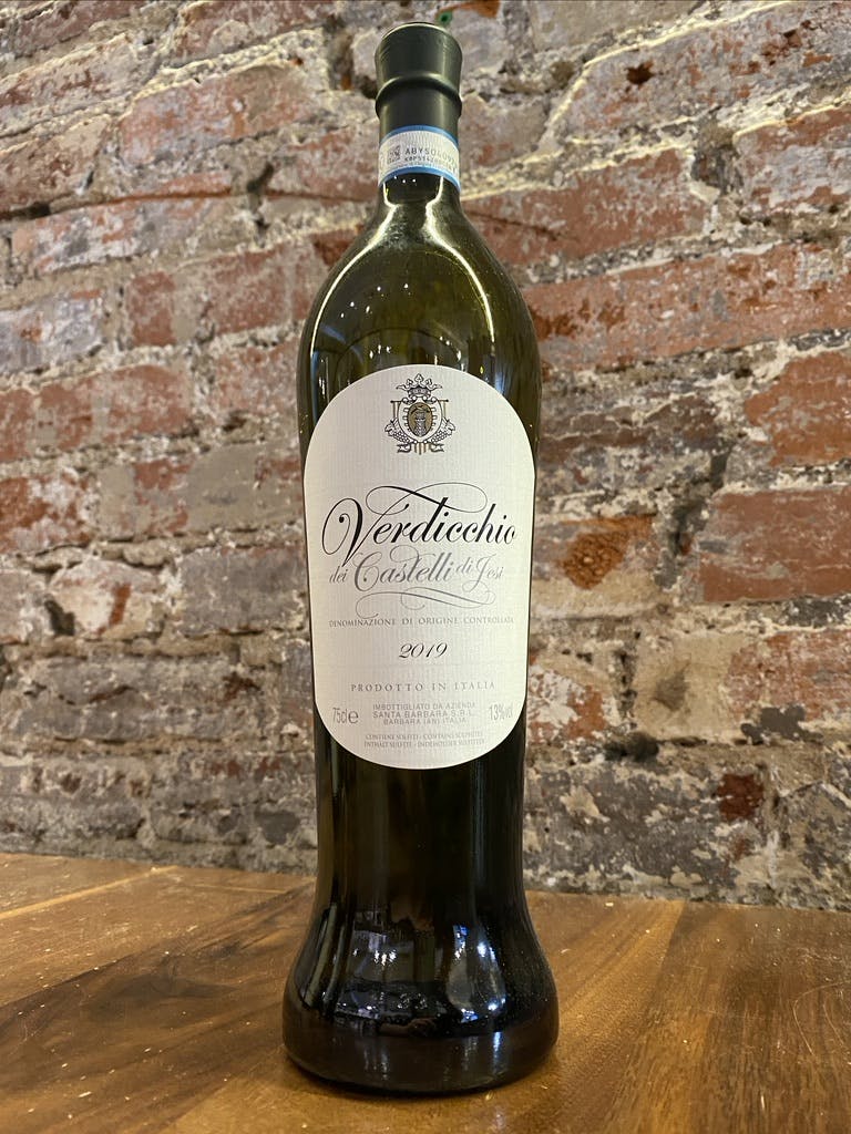 a bottle of wine next to a brick wall