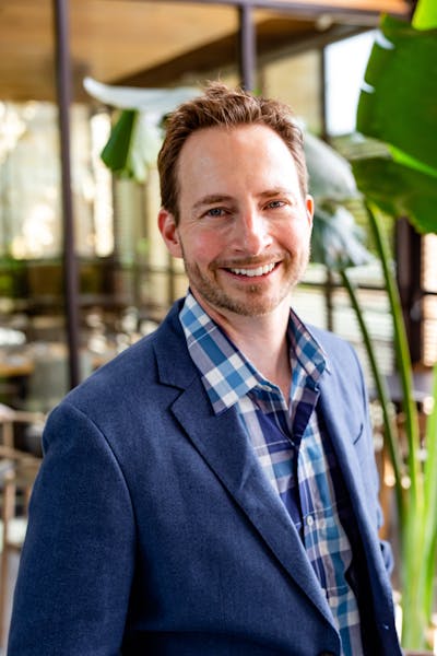a man wearing glasses and smiling at the camera