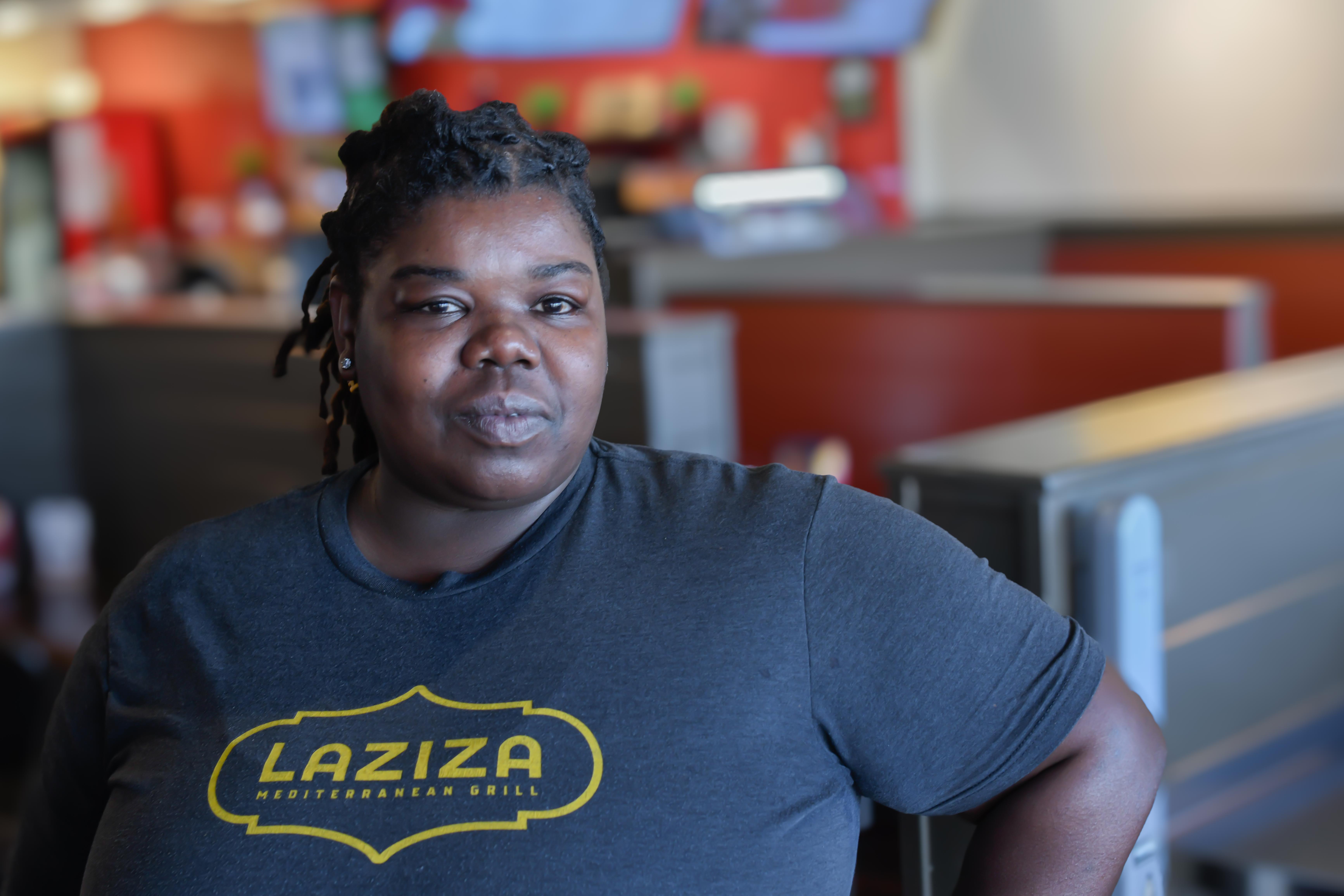 a person sitting at a table with a laptop and smiling at the camera