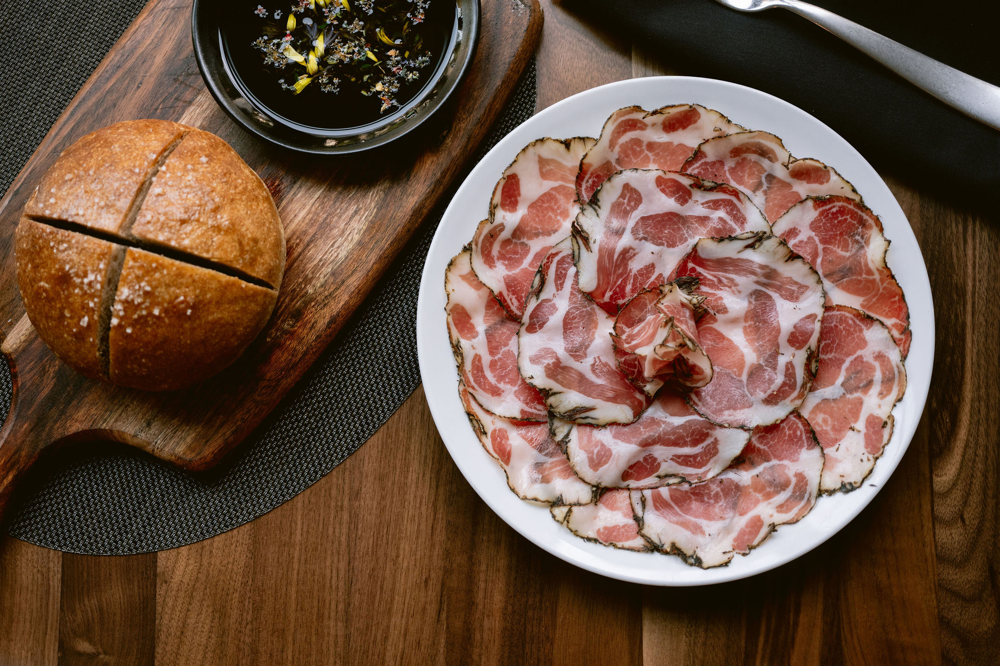 a plate of meat and bread on a cutting board