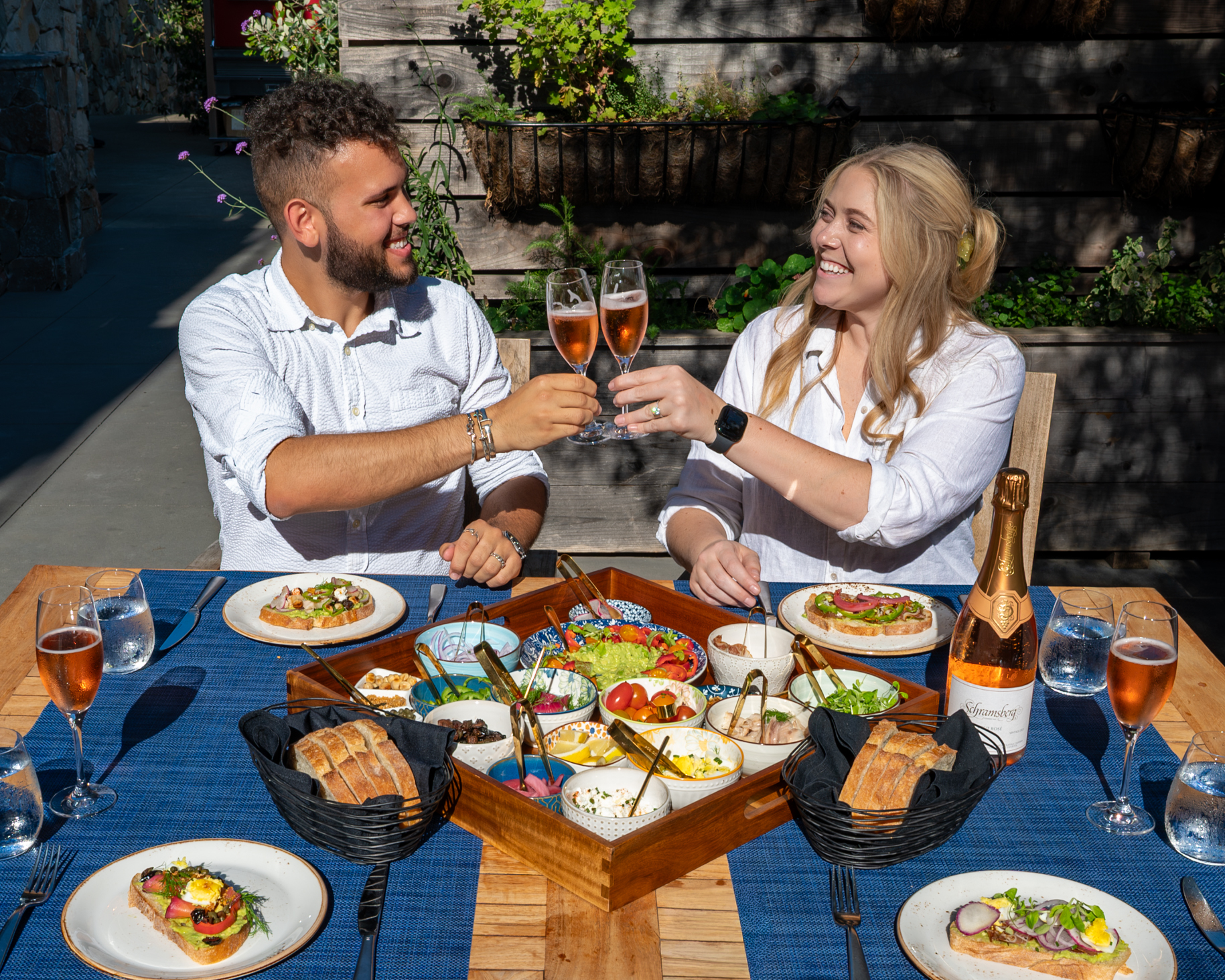 a man and woman sitting at a table with food and drinks
