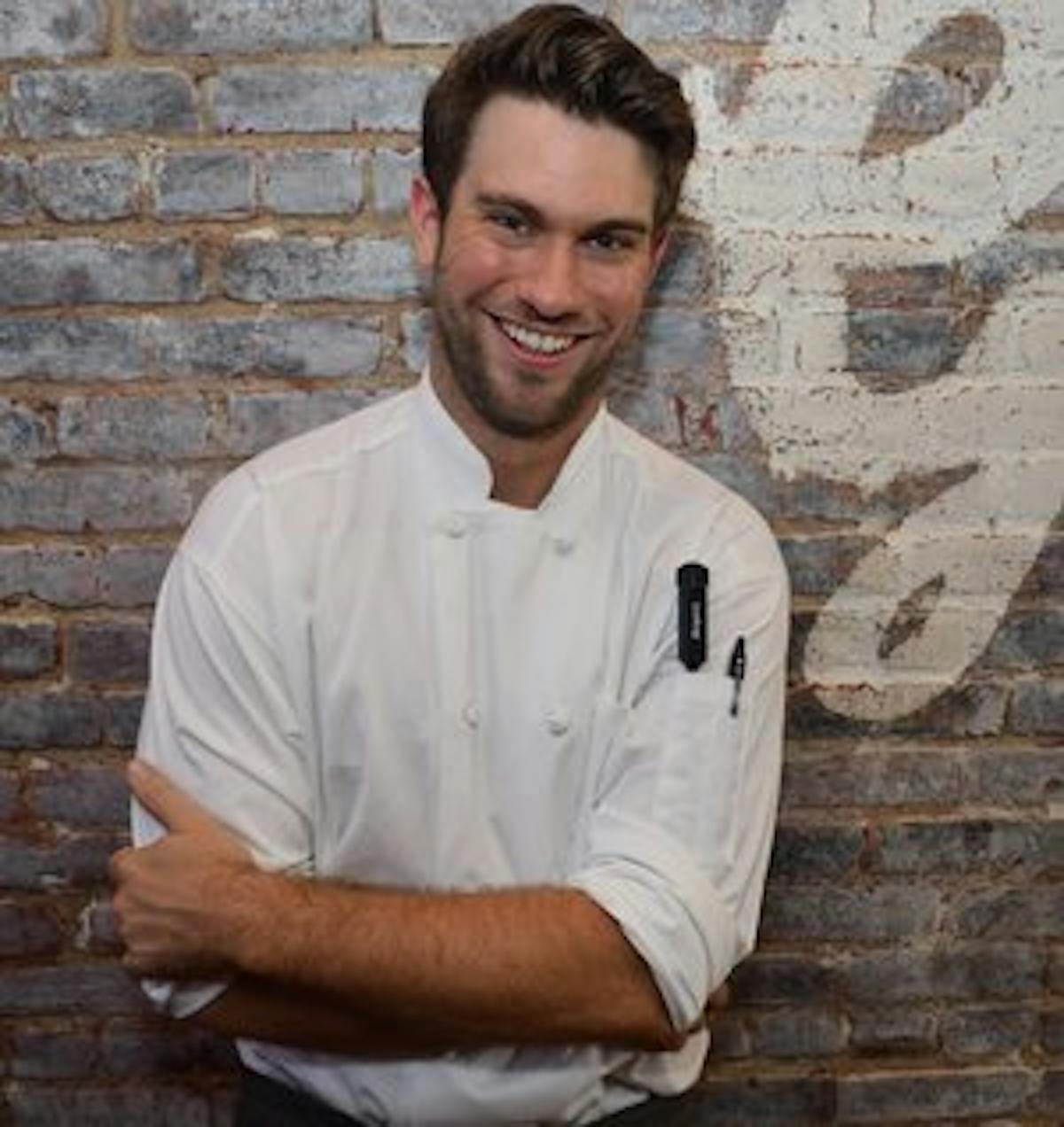 a man standing in front of a brick wall