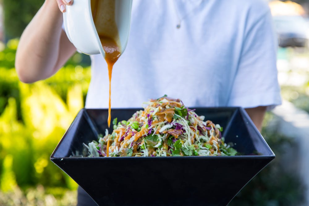 a person standing in front of a bowl of salad