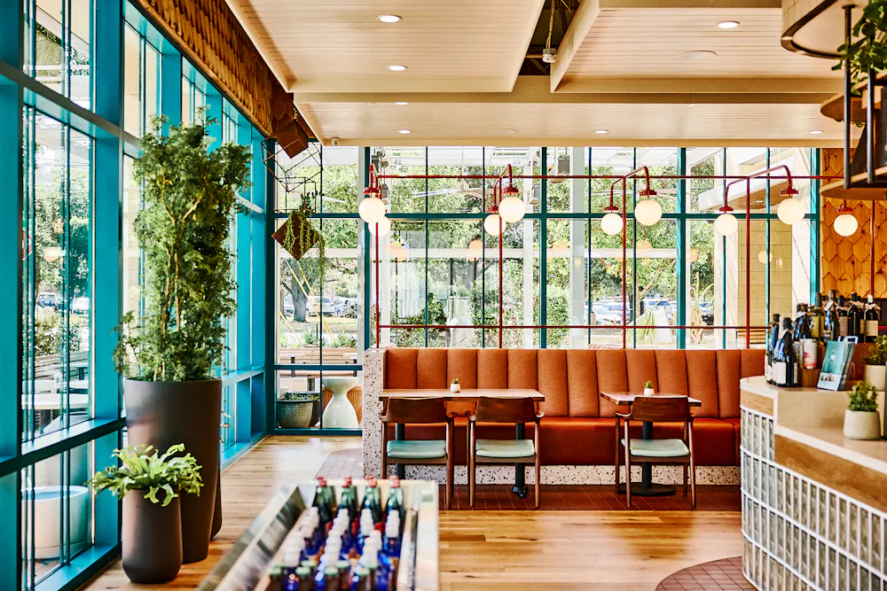 a room with a booth and tables and plants