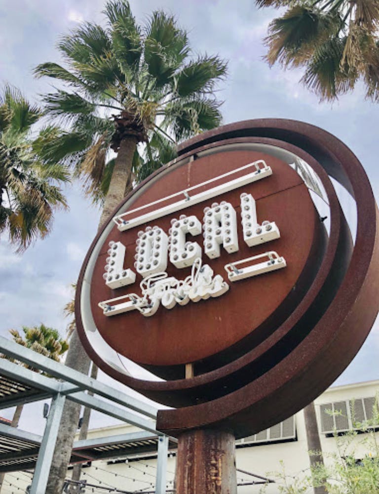 a sign in front of a palm tree