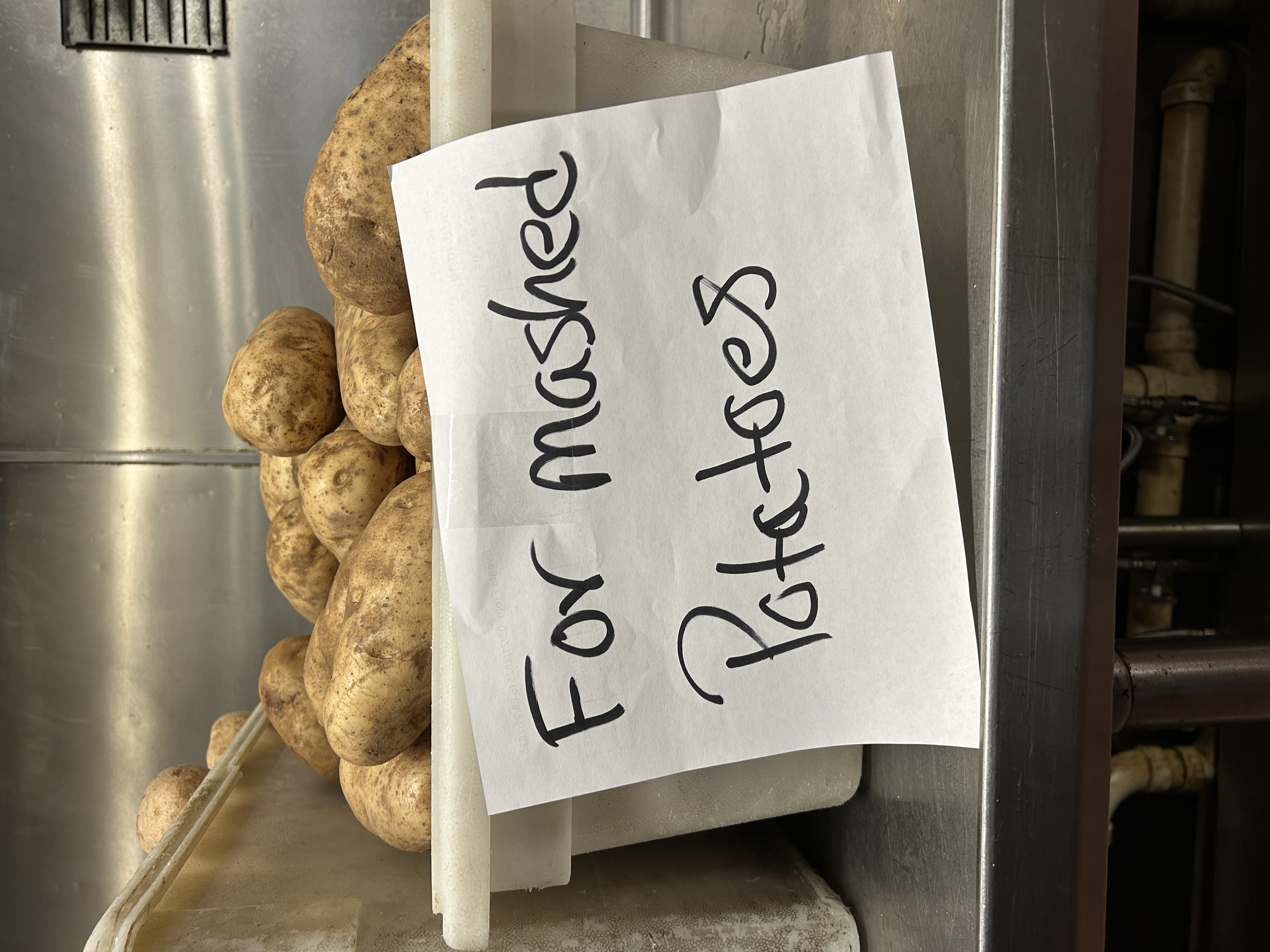 a container of potatoes with a sign