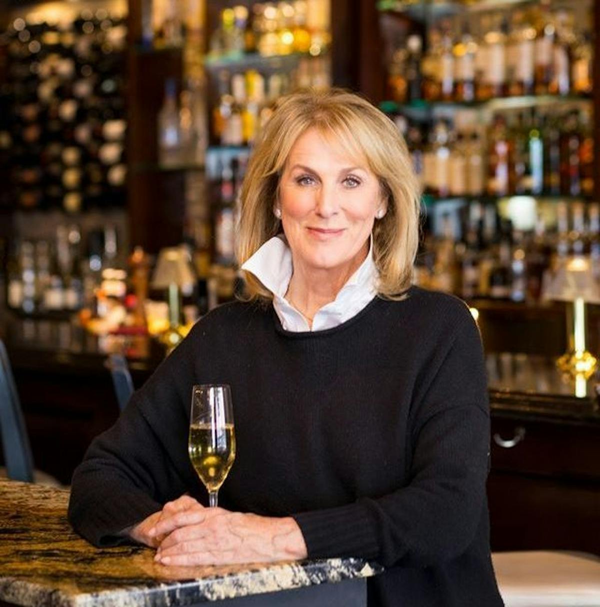 a woman sitting at a table with wine glasses