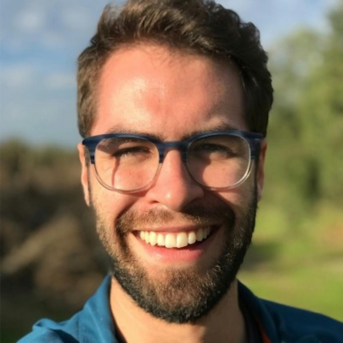 a man wearing glasses and smiling at the camera