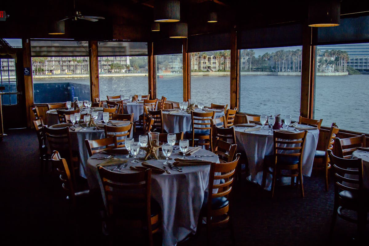 tables and chairs in a room that overlooks the water