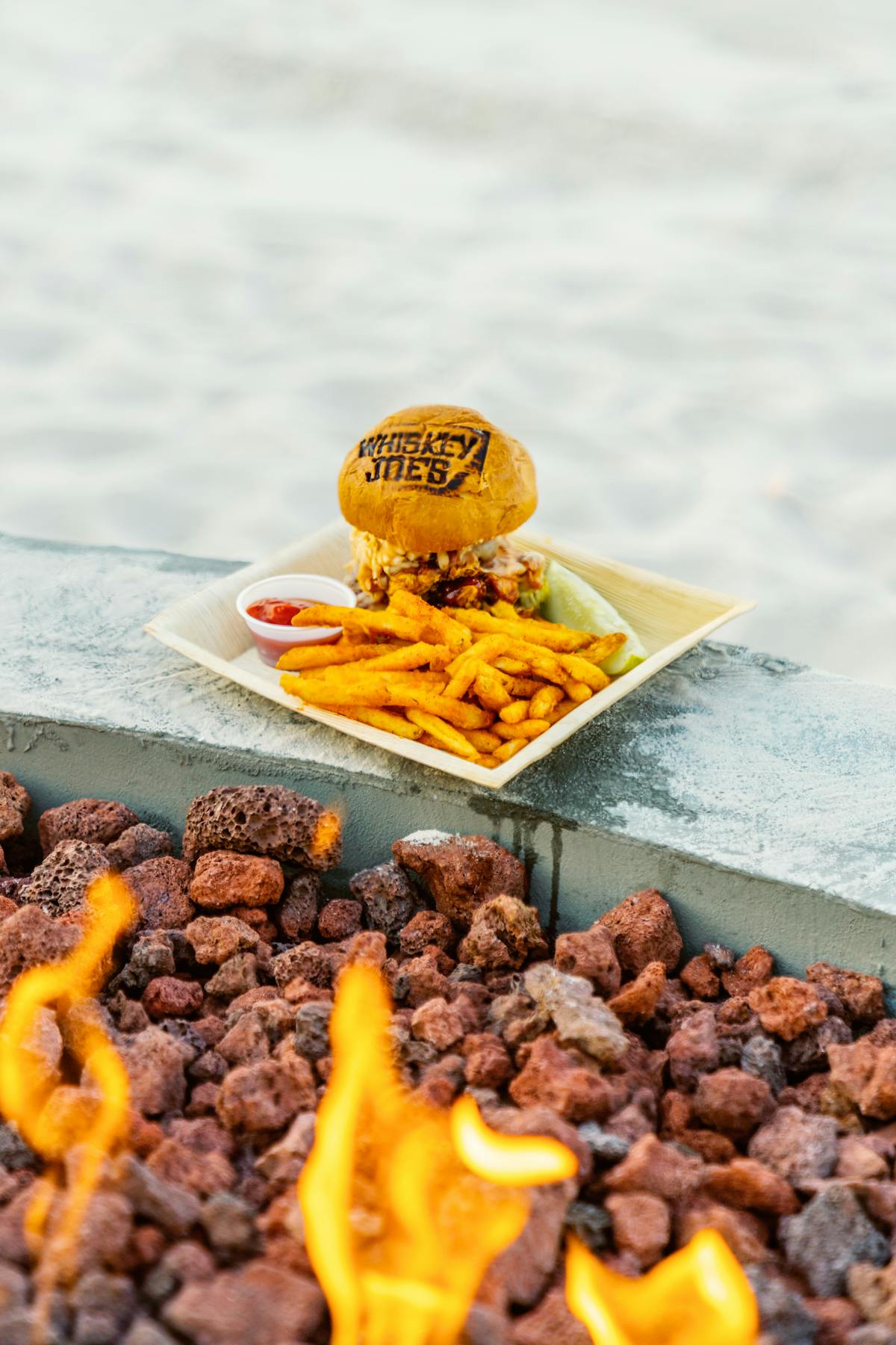 a burger and fries sitting on a fire pit