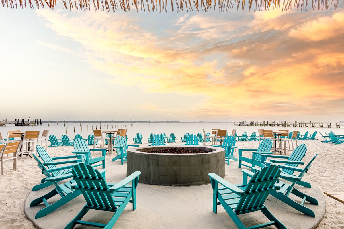 a fire pit on the beach during sunset