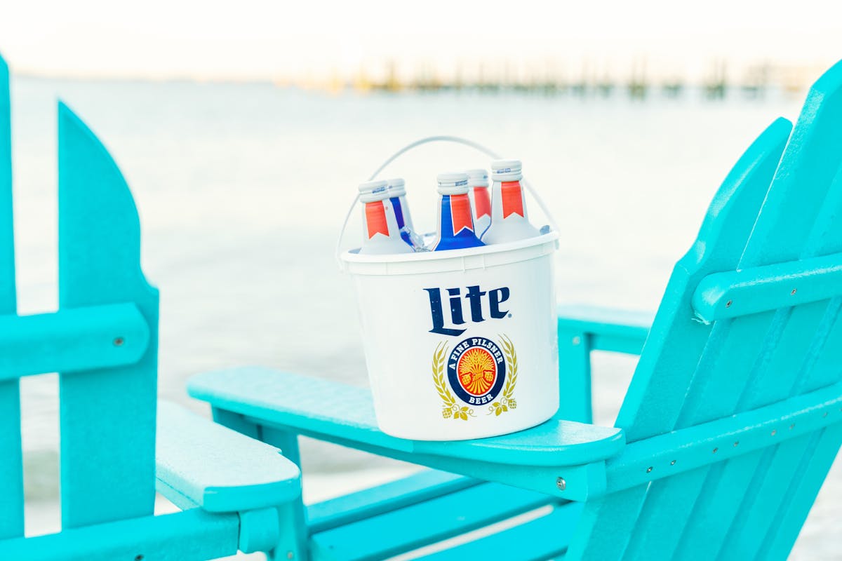 a bucket of long neck beer bottles on beach chair