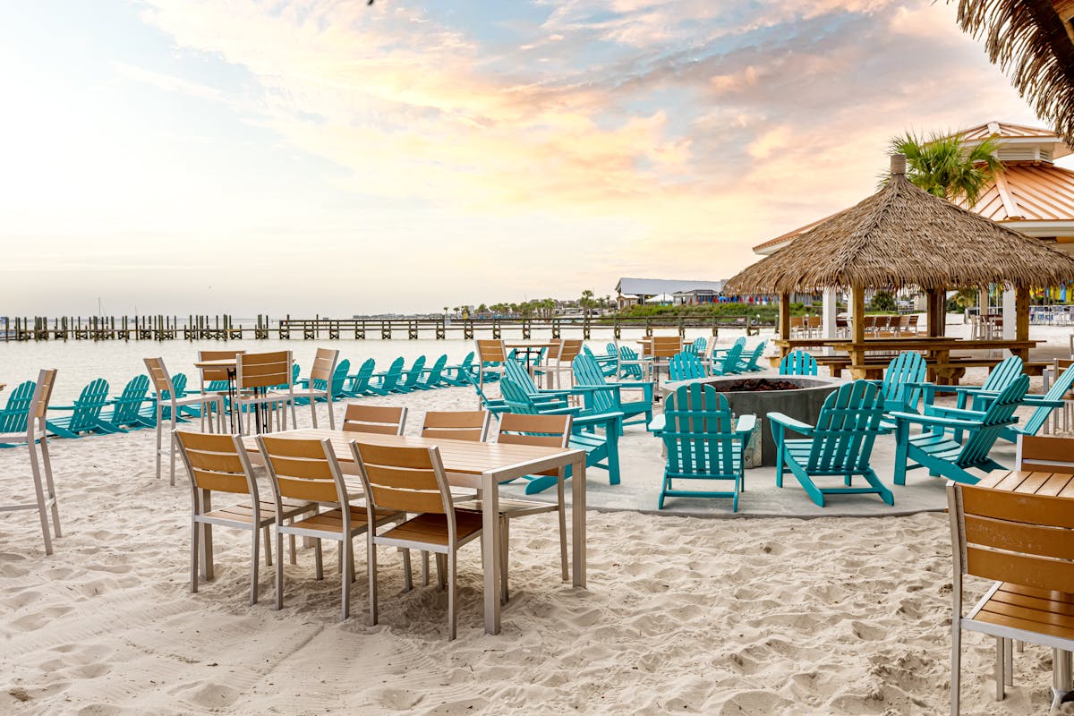 tables and chairs on the beach during sunset